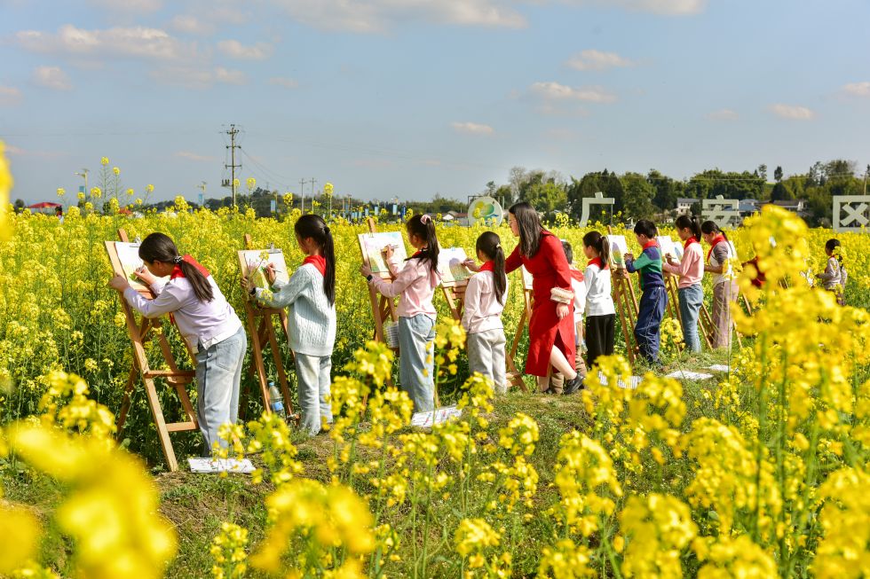 在四川省广安市广安区花桥镇花桥村，小学生在油菜花田间绘画（2026年3月10日摄）。新华社发（张国盛摄）